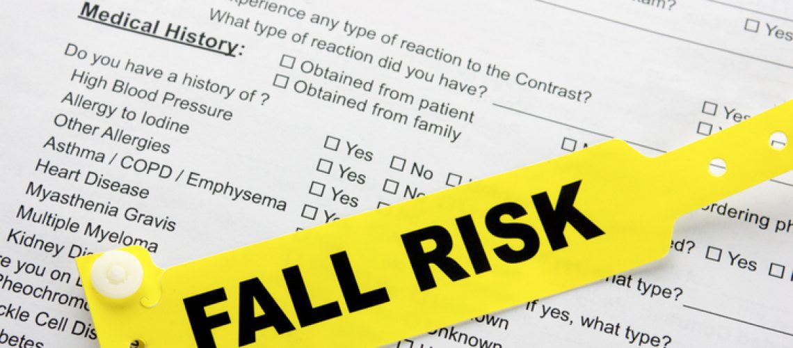 A yellow fall risk patient bracelet on top of a hospital questionnaire paperwork